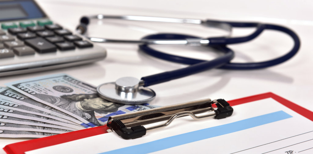 Desk with a clipboard, calculator, stethoscope, and money representing the discussion of travel nurse pay rates.