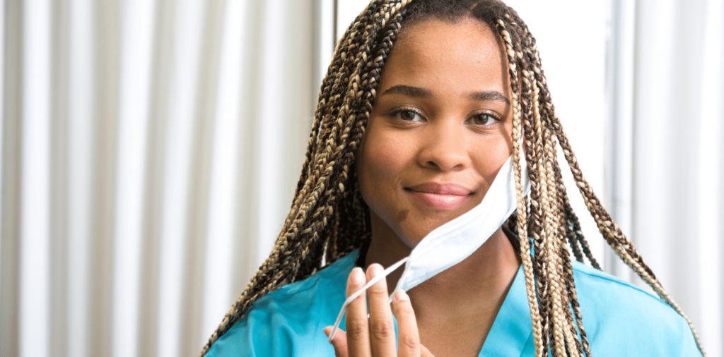 Travel nurse celebrating the World Health Organization's declaration of the end of COVID-19, removing her mask with a smile on her face.