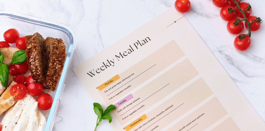 A set of meal prep containers filled with a variety of food items, neatly arranged on a marble counter. Next to the containers, there is a weekly meal plan displayed, outlining the different meals for each day of the week.